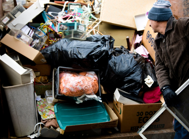 a man putting junk in a trash pile